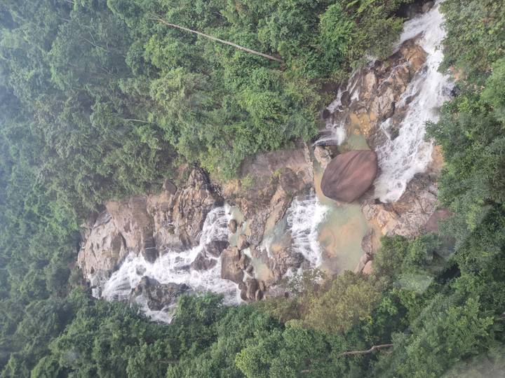 Cascada fluyendo sobre rocas en bosque exuberante.