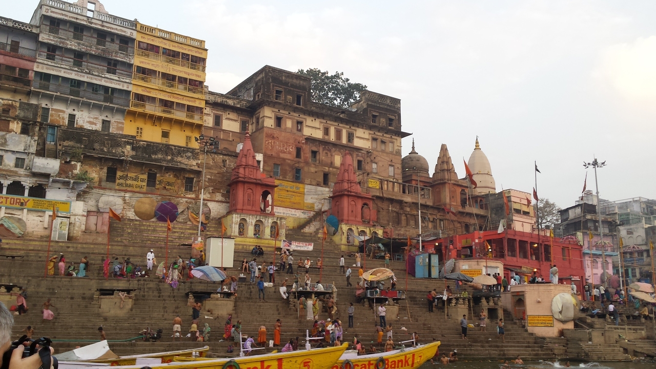 Busy ghats of Varanasi with colorful historic buildings, temples, and people along the Ganges.