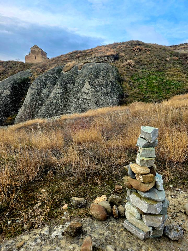 Pila de piedras en un campo herboso con rocas.