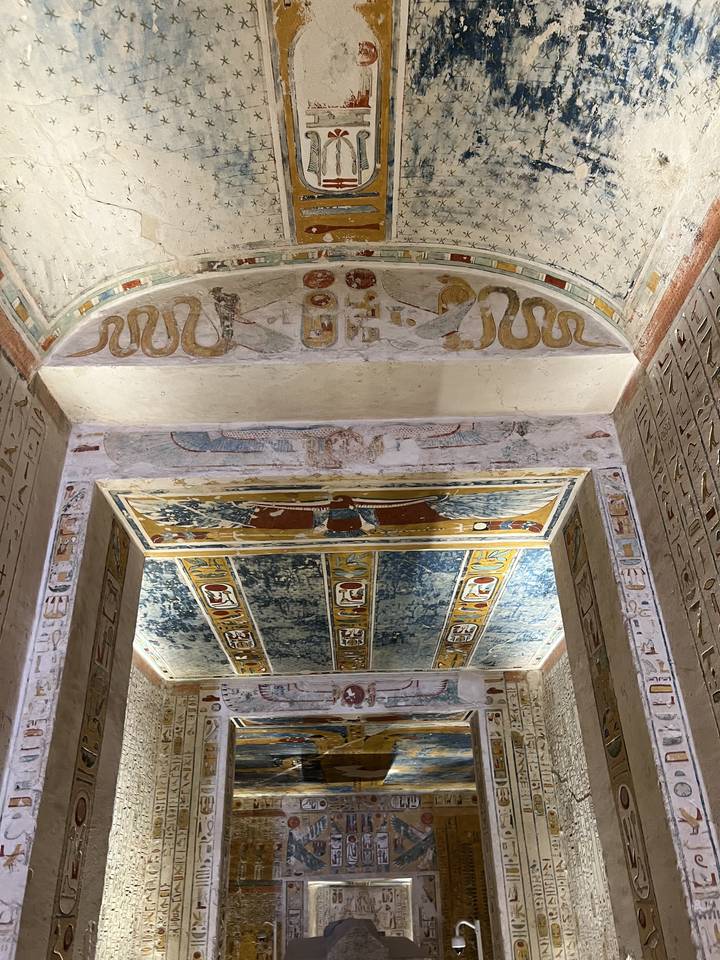 Intérieur d'une tombe égyptienne avec des hiéroglyphes et des peintures murales colorés.