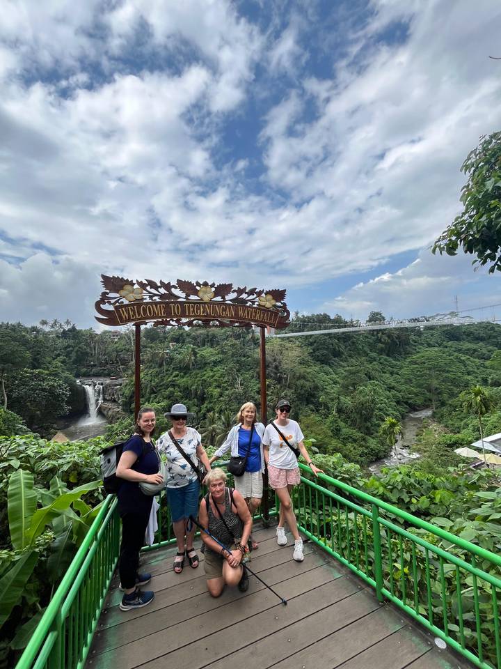 Des touristes à l'entrée d'un parc de cascades posant pour une photo.