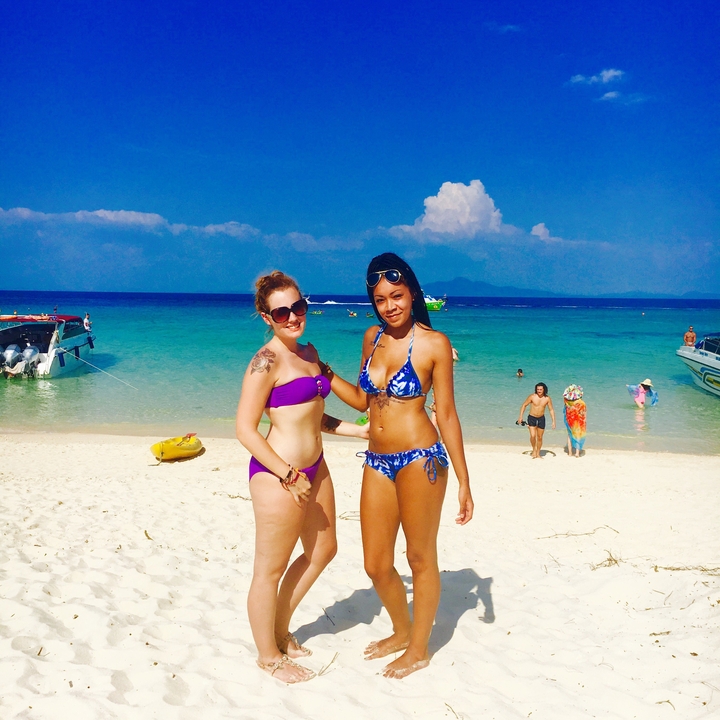 Two women posing on a sunny beach.