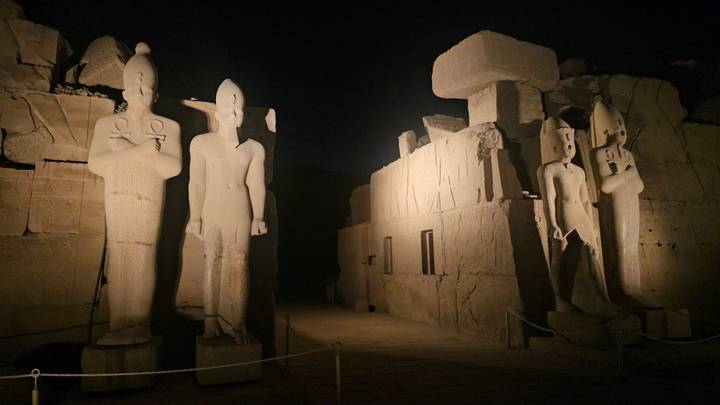 Statues antiques illuminées la nuit.