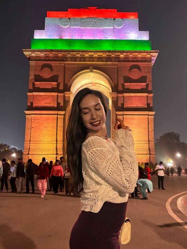 Femme qui pose la nuit devant un monument éclairé.