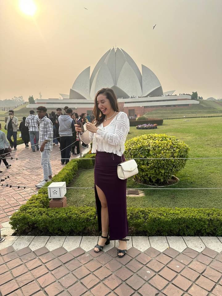 Touriste pose joyeusement devant un célèbre monument en forme de lotus.