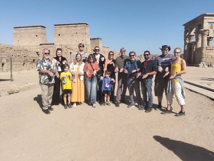Group of tourists posing near ancient ruins in a desert setting.