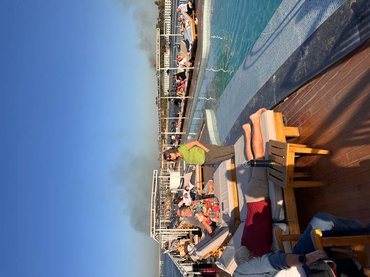 People relaxing on sun loungers by a pool on a cruise.