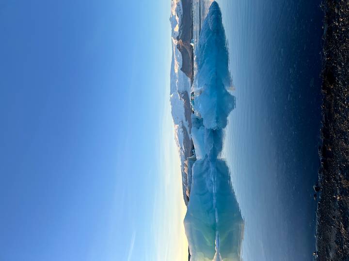 Glacier se reflétant dans des eaux calmes sous un ciel dégagé.