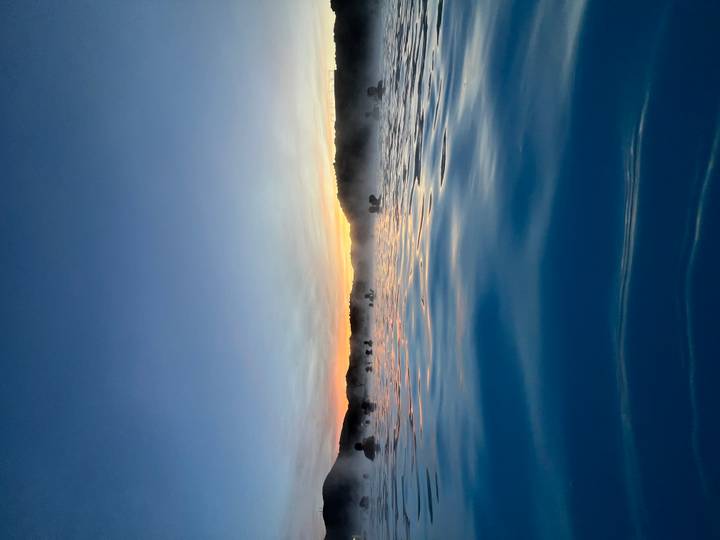 Des gens se détendent dans un lagon bleu vapeureux au lever du soleil.