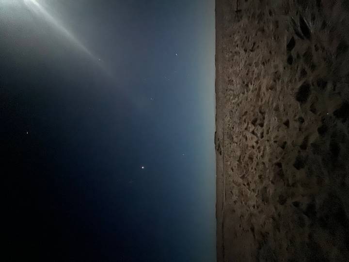 Ciel nocturne rempli d'étoiles au-dessus d'un paysage désertique de sable.