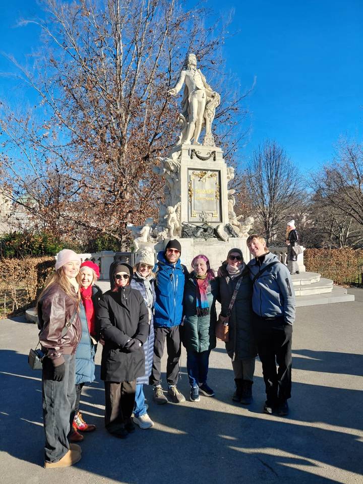 Grupo de turistas posando frente a una estatua con inscripciones.