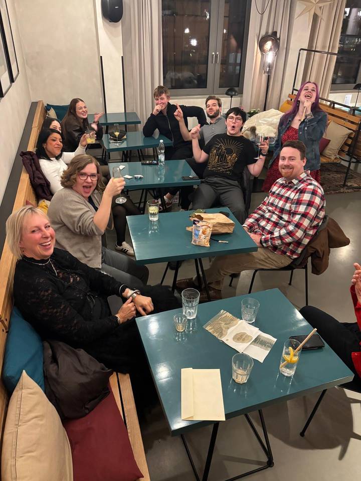 Grupo de amigos disfrutando bebidas y aperitivos en interiores.