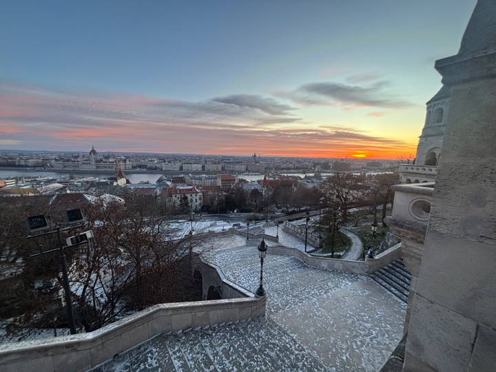 Vista del paisaje urbano con río y atardecer distante.