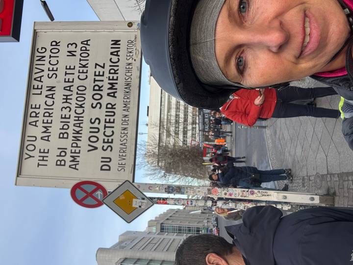Persona posando frente a un letrero histórico de Berlín.