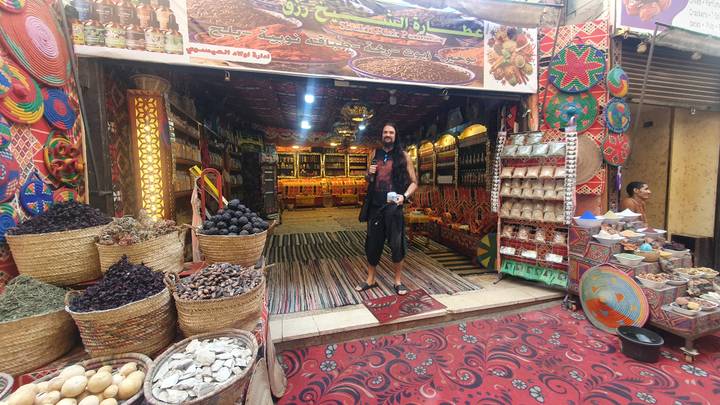 Persona parada afuera de una tienda de especias colorida en un mercado.