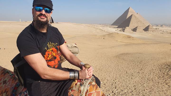 Persona sentada en un camello frente a las Pirámides de Giza.