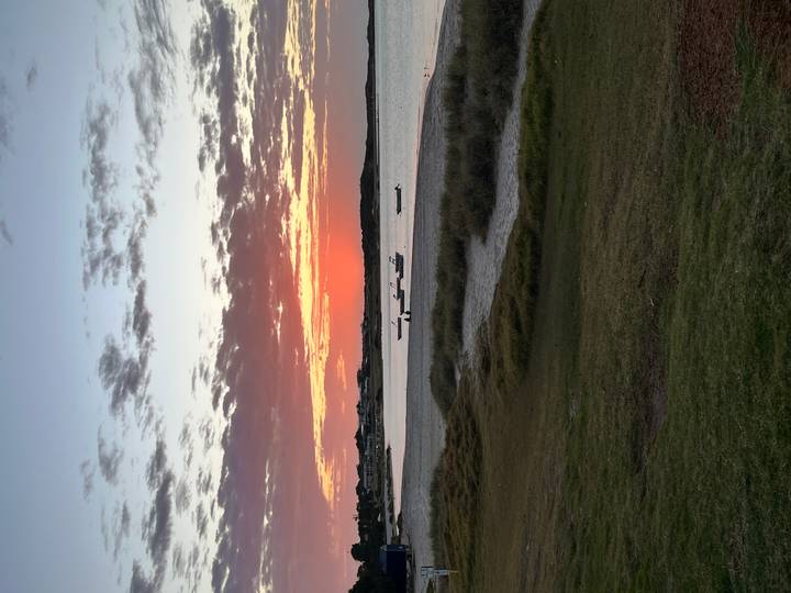 Boats on a calm sea with sunset in the background.