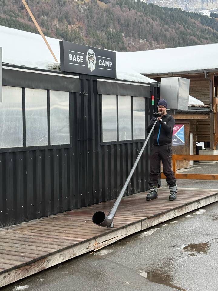 Persona usando bastones de esquí junto a un edificio en un área nevada.