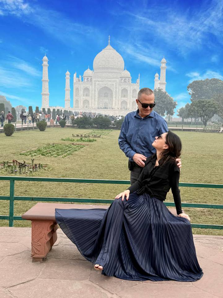 Pareja sentada junta con el Taj Mahal de fondo.