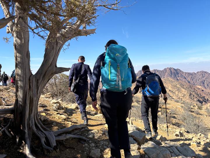 Randonneurs marchant sur un sentier rocheux avec une vue panoramique sur les montagnes.