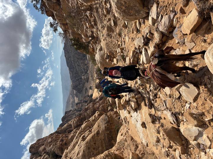 Groupe de touristes avec un âne marchant à travers un paysage désertique.