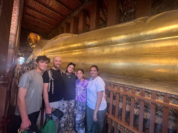 Grupo de personas frente a un gran Buda dorado reclinado.