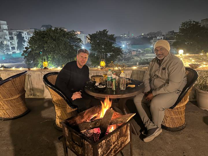 Dos personas cenando al aire libre por la noche con una fogata.