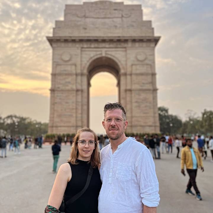 Deux touristes debout devant India Gate avec une foule de gens autour.