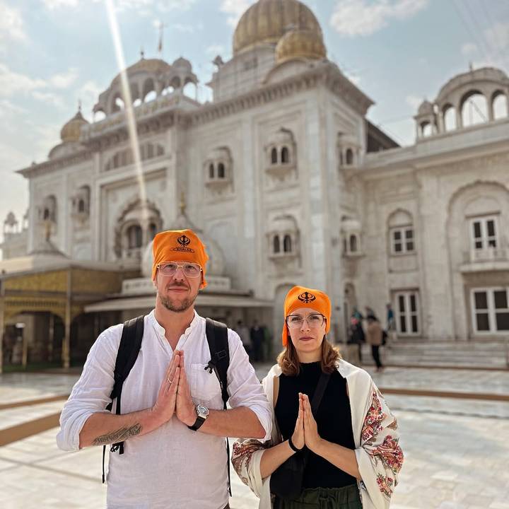 Deux touristes posant devant un temple sikh, portant des couvre-chefs orange.