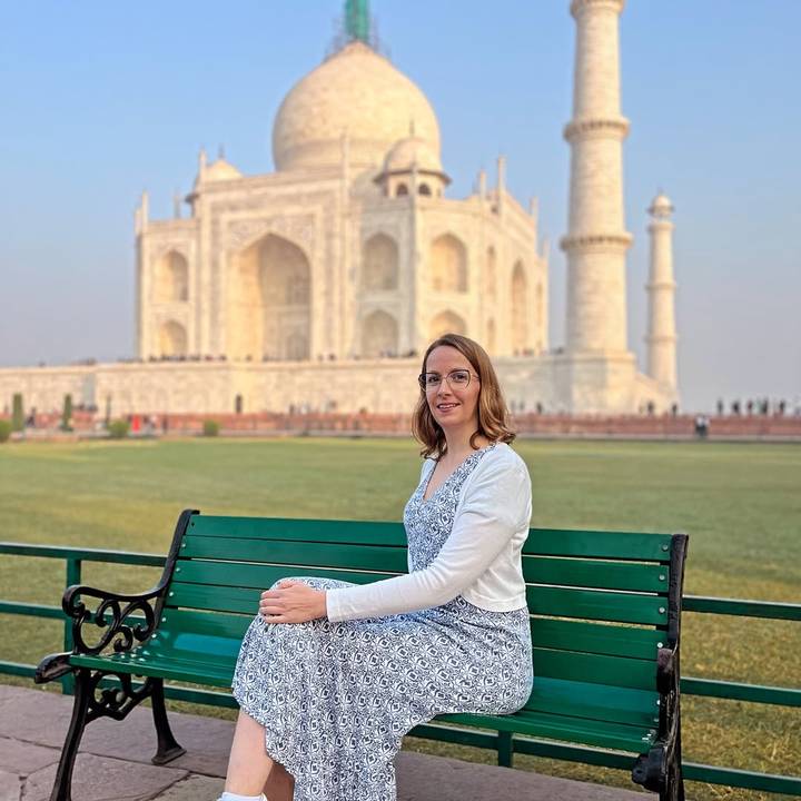 Une femme assise sur un banc avec le Taj Mahal en arrière-plan.
