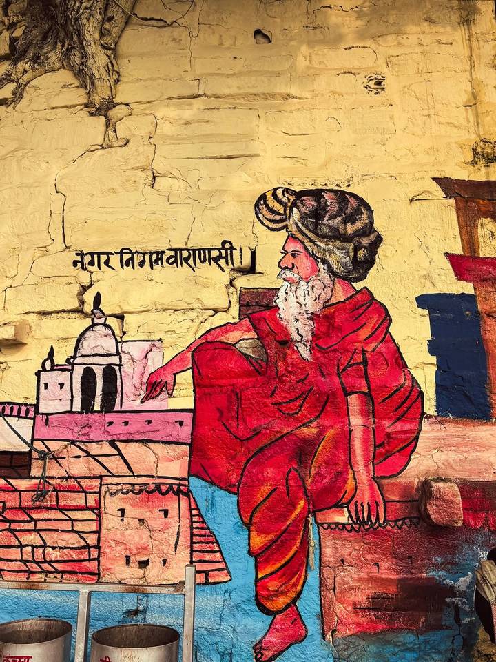 Peinture murale vibrante représentant un sage assis en tenue traditionnelle avec du texte hindi.