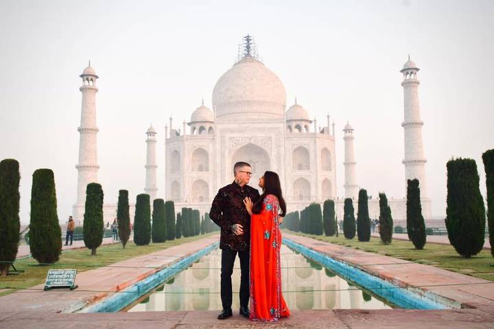 Couple debout devant le Taj Mahal.
