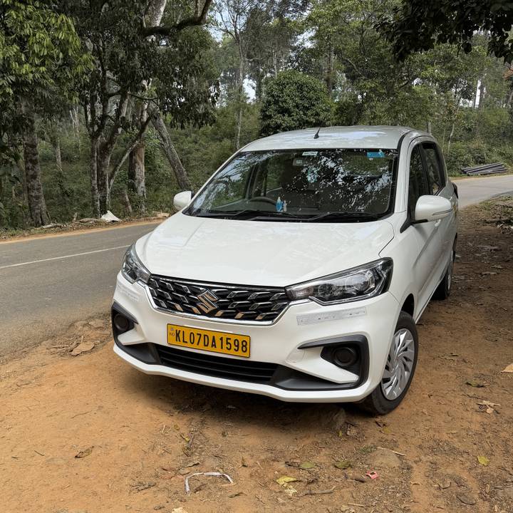 Voiture blanche garée au bord de la route avec des arbres.