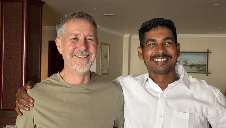 Deux hommes souriants posant ensemble à l'intérieur.