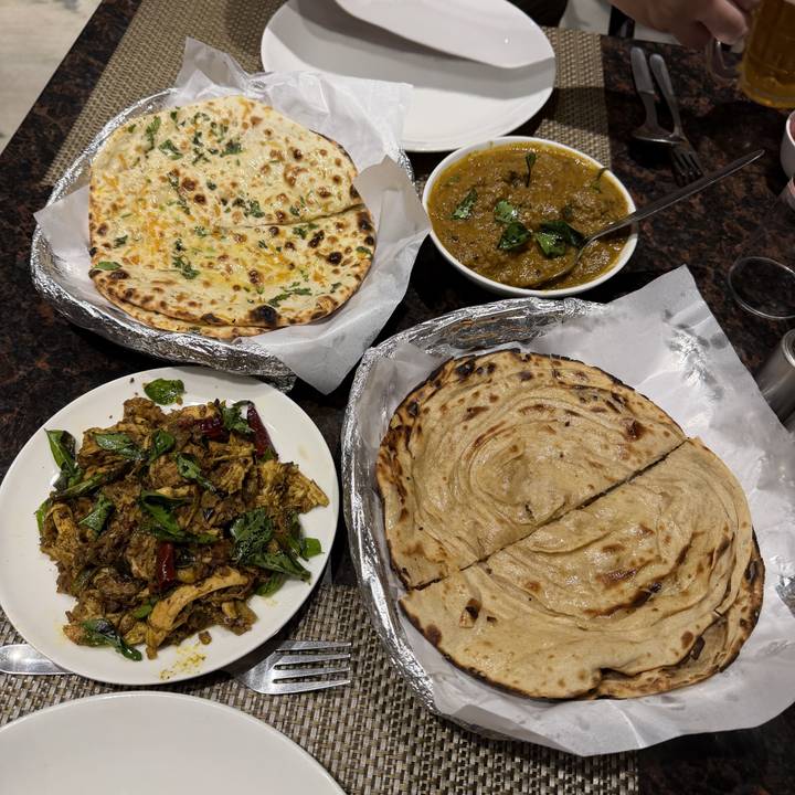 Différents plats comprenant du naan et du curry disposés sur une table.