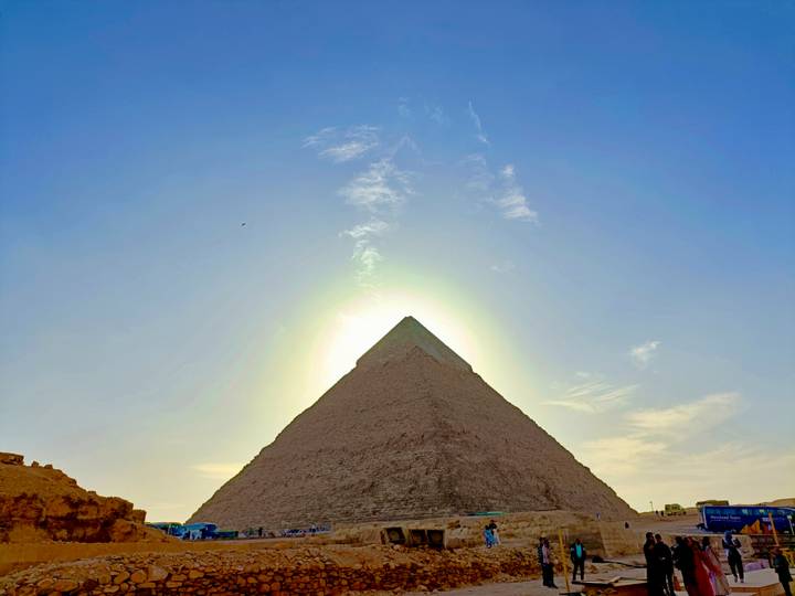 Une pyramide à Gizeh avec le soleil derrière elle.