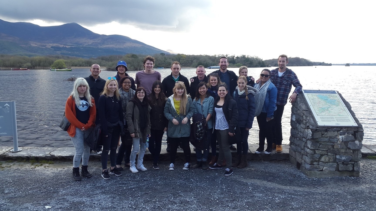 Groupe de personnes posant près d'un monument en pierre au bord d'un lac.