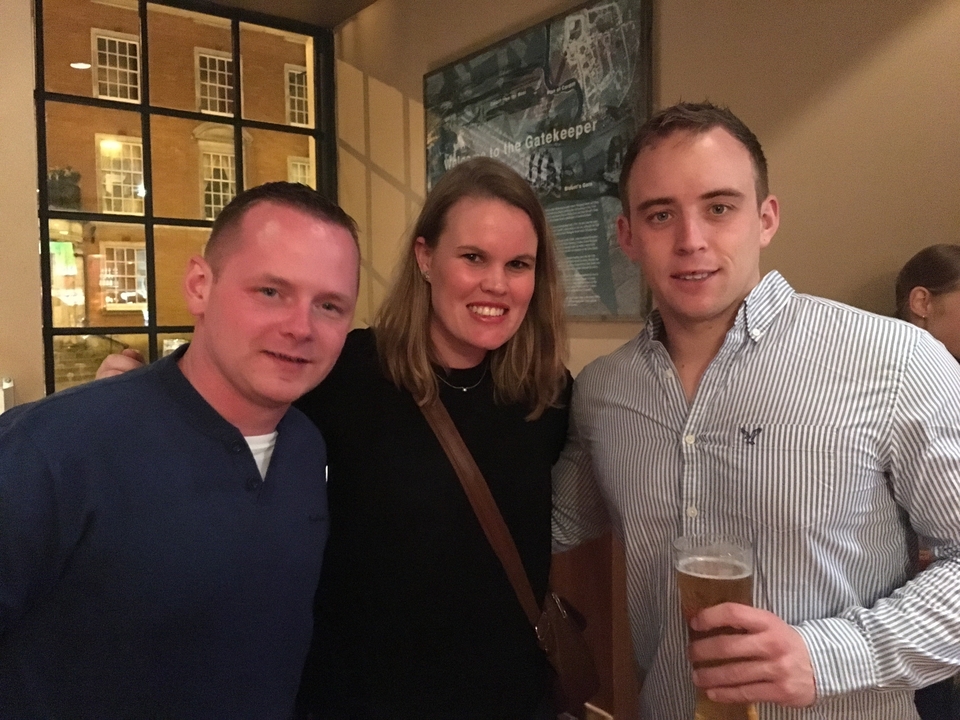 Trois personnes posant à l'intérieur en tenant des boissons.