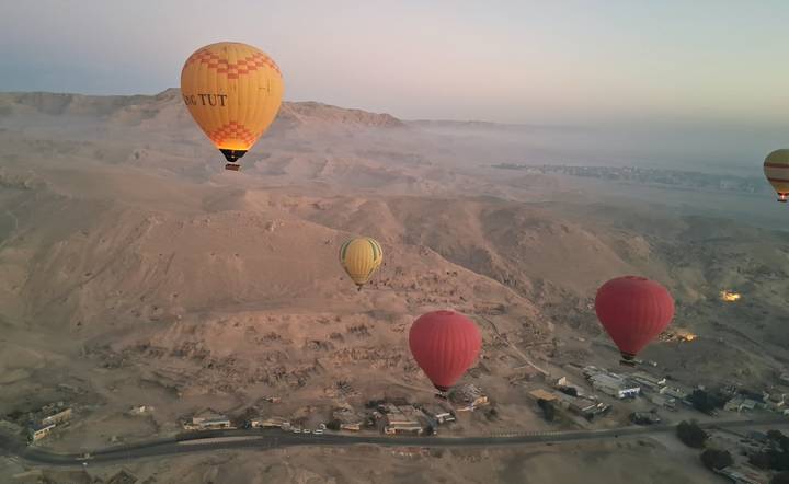 Aerial view of a desert landscape with multiple hot air balloons.