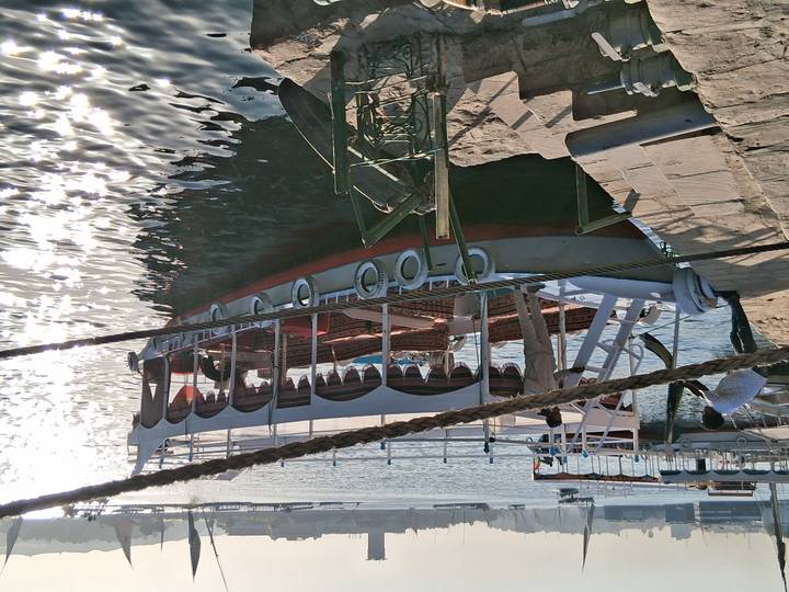 Traditional boat docked at the riverside, shimmering on the water.