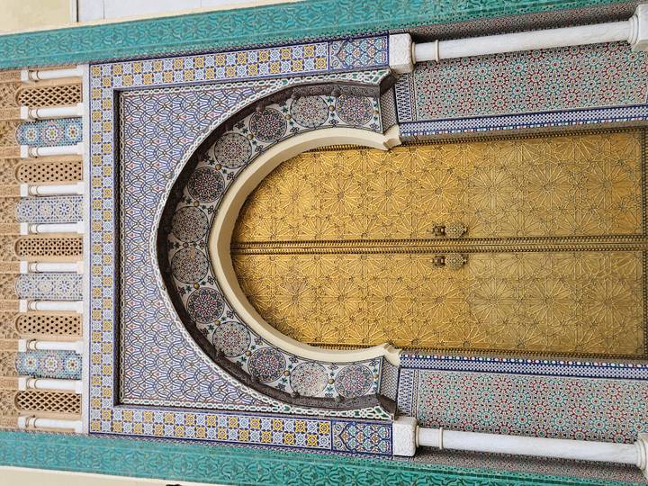 Ornate arched door with intricate tile designs in Morocco.