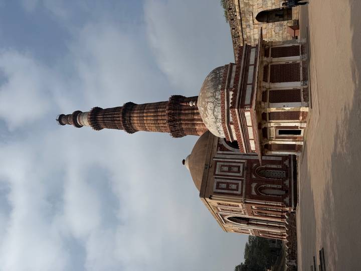 Complejo Qutub Minar con un minarete antiguo y edificios circundantes.