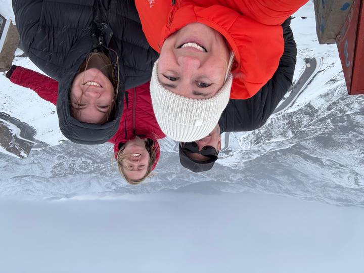 Quatre personnes posant sur une montagne enneigée avec une vue panoramique.