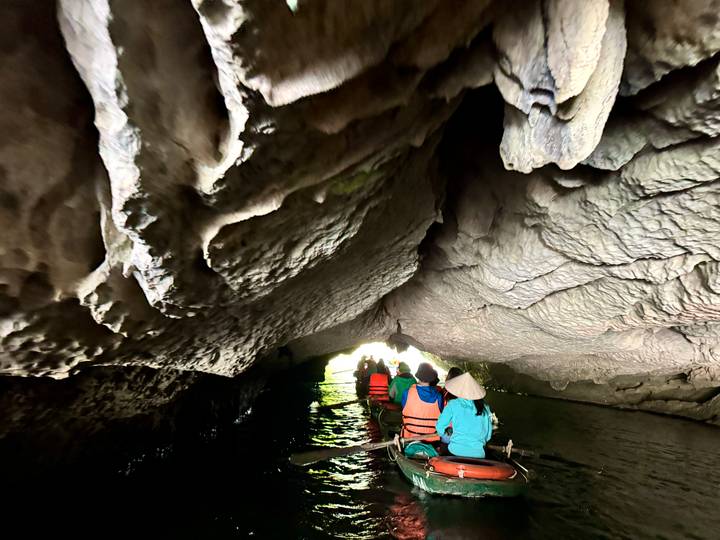 Personas navegando en kayak a través de una cueva con techo bajo.