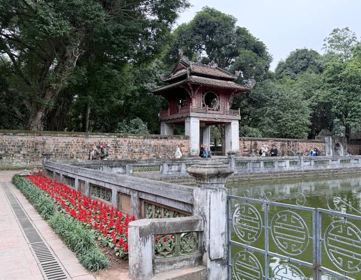 Templo con gran patio, árboles y gente sentada.