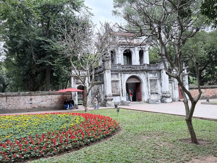 Templo ornamentado con jardín circundante y gente alrededor.