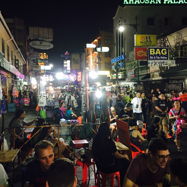 Bustling night market street filled with neon signs, stalls, and crowds of shoppers.