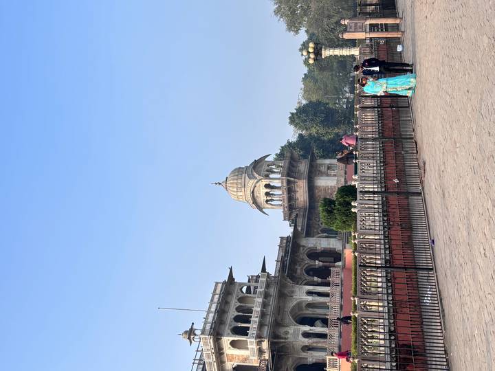 Bâtiment historique orné avec un dôme, des gens qui passent.