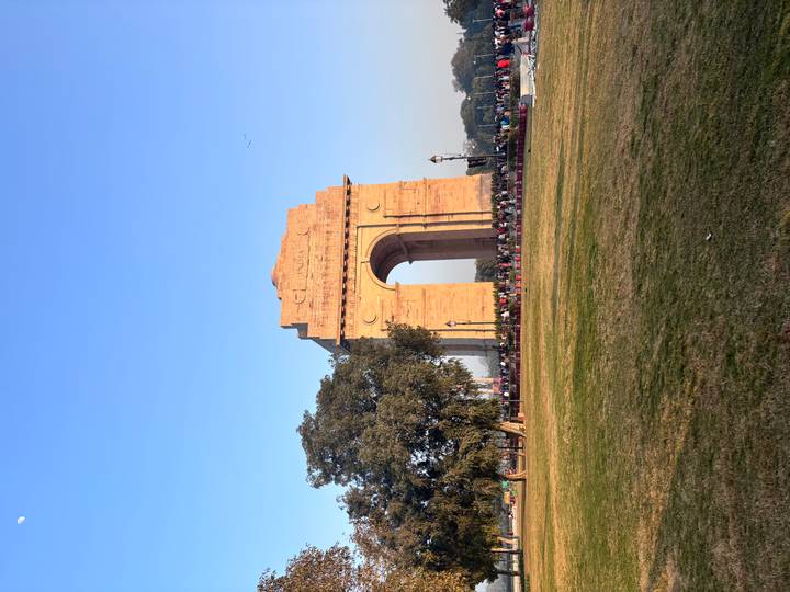 Porte de l'Inde avec des gens au premier plan, ciel bleu dégagé.