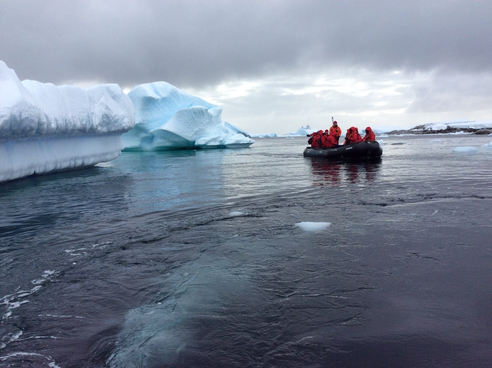 Groupe dans un petit bateau naviguant sur des eaux glacées.